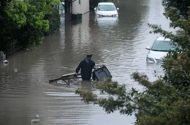 A security guard carries a dustbin along a flooded street, during a heavy rainfall, in Shanghai, August 24, 2015. (Photo by Reuters/China Daily)