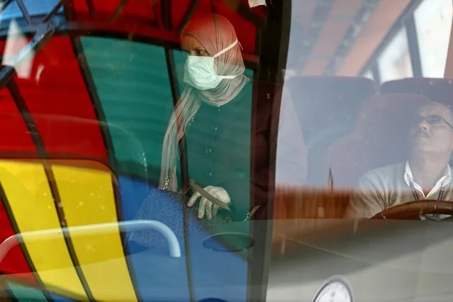 A Palestinian woman, wearing a mask as a preventive measure against coronavirus, alights from a bus upon her return from abroad, at the Israeli-controlled Allenby Bridge crossing in Jericho, in the Israeli-occupied West Bank on March 10, 2020. (Photo by Ammar Awad/Reuters)