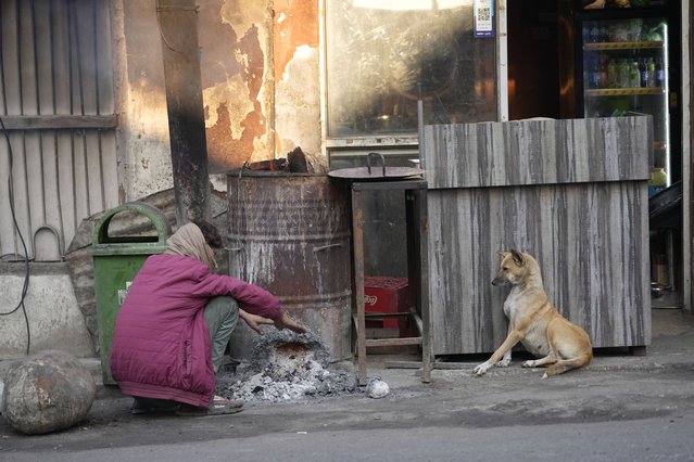 A man sits near fire to keep warm on a cold morning in Jammu, India, Friday, November 29, 2024. (Photo by Channi Anand/AP Photo)