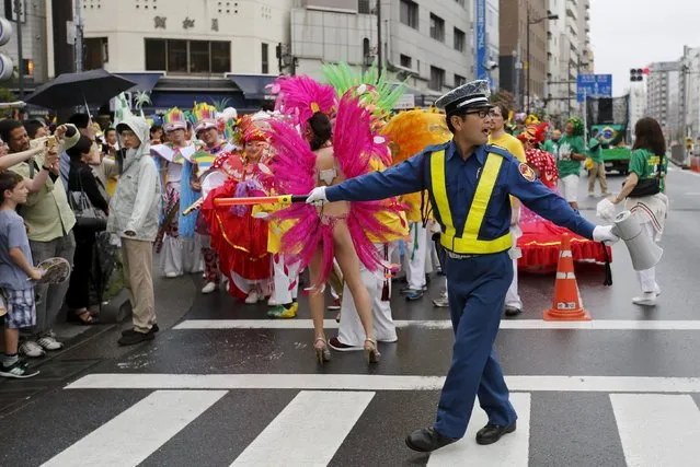 A security staff, standing near dancers after their performance, directs traffic during the 34th annual Asakusa Samba Carnival in Tokyo August 29, 2015. (Photo by Toru Hanai/Reuters)