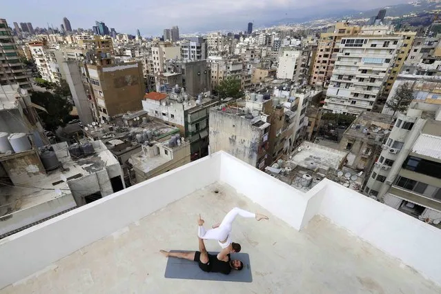 Lebanese Yoga instructor Rabih el-Medawar, 29, practises Acroyoga with his Ukranian wife, fellow Yoga instructor and professional choreographer, Alona Aleksandrova, 24, on the roof of their apartment building in Beirut's Ain El-Remmaneh district on April 27, 2020 during the coronavirus (COVID-19) virus epidemic. (Photo by Joseph Eid/AFP Photo)