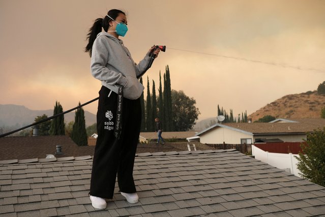 Kayla Amara sprays down their home as the Hughes Fire burns in Castaic, California, U.S. January 22, 2025. (Photo by Joel Angel Juarez/Reuters)