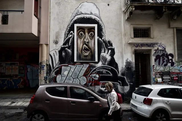A woman walks past graffiti by a Bali born street artist WD (Wild Drawing) in central Athens on October 11, 2017. An ongoing exhibition devoted to “Artists in Athens, City of Crisis” is taking place in the Greek capital. “Every wall of abandoned buildings is a canvas for us” says Greek Greek street artist Cacao Rocks and explains how the Greek capital hit by the financial crisis and then that of the migrants, is transformed into an “international meeting point” of Greek street art. (Photo by Louisa Gouliamaki/AFP Photo)