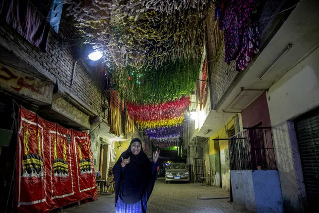 A woman walks on a street under decorations a day ahead of the holy month of Ramadan, in the Imbaba neighborhood of Giza, April 23, 2020. Muslims around the world are trying to maintain the cherished rituals of Islam holiest month during the coronavirus pandemic. (Photo by Nariman El-Mofty/AP Photo)