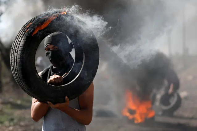 A Palestinian protester carries a burning tire during clashes with Israeli troops, in the West Bank village of Kofr Qadom, near the West Bank city of Nablus November 3, 2017. (Photo by Mohamad Torokman/Reuters)
