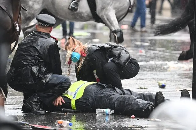 A colleague attends to a police officer who was injured when falling of a horse during scuffles with demonstrators at Downing Street during a Black Lives Matter march in London, Saturday, June 6, 2020, as people protest against the killing of George Floyd by police officers in Minneapolis, USA. Floyd, a black man, died after he was restrained by Minneapolis police while in custody on May 25 in Minnesota. (Photo by London News Pictures)