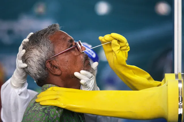 An employee of the Mugda Medical College and Hospital collects a swab sample from a resident to test for the COVID-19 coronavirus, in Dhaka on June 17, 2020. Worldwide more than eight million people have been infected by COVID-19 and over 439,000 have died, with the virus accelerating across South Asia and Latin America. (Photo by Munir Uz Zaman/AFP Photo)