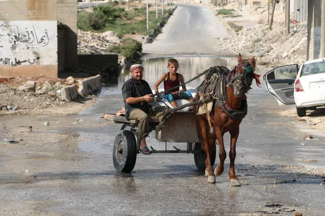 A man and a boy ride a cart pulled by a horse in the rebel held neighbourhood of Sheikh Saeed, in Aleppo, Syria  August 20, 2016. (Photo by Abdalrhman Ismail/Reuters)