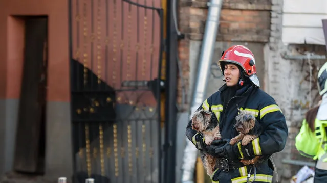 A rescuer carries two dogs outside the damaged 101 Tower skyscraper in Kyiv following Russian shelling on October 10, 2022. (Photo by Serhiy Nuzhnenko/Radio Free Europe/Radio Liberty)