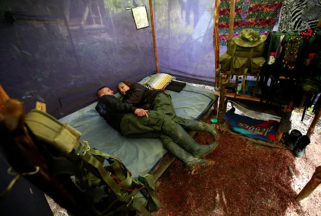 A couple from the 51st Front of the Revolutionary Armed Forces of Colombia (FARC) rest inside a tent at a camp in Cordillera Oriental, Colombia, August 16, 2016. (Photo by John Vizcaino/Reuters)