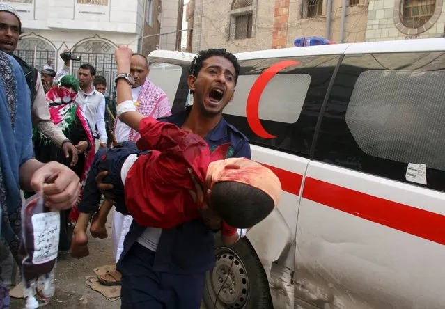 A man shouts as he carries a boy injured by a shell that landed in a residential area during fighting between Houthi militants and pro-government militants in Yemen's southwestern city of Taiz September 24, 2015. (Photo by Reuters/Stringer)
