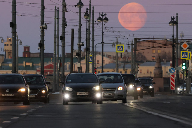 People drive cars during early morning hours, with the moon seen in the background, in Saint Petersburg, Russia, on March 17, 2025. (Photo by Anton Vaganov/Reuters)