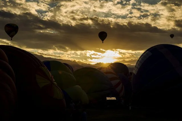 Hot air balloons lift off as the sun rises over the first day of the 2015 Albuquerque International Balloon Fiesta in Albuquerque, New Mexico, October 3, 2015. (Photo by Lucas Jackson/Reuters)