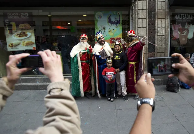 Children pose with street performers dressed as the three wise men, as part of celebrations ahead of Three Kings Day, in the historic center of Mexico City, Friday, January 5, 2018. (Photo by Rebecca Blackwell/AP Photo)