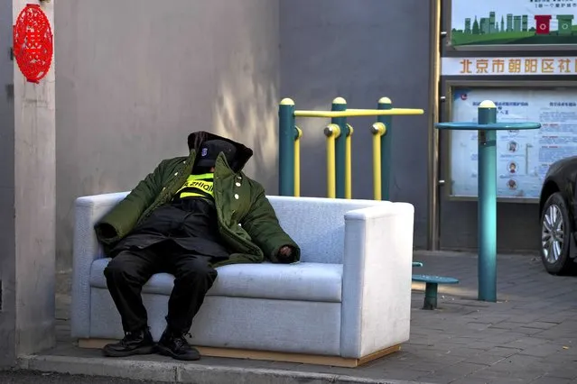 A security guard takes a nap on a sofa placed near the exercise equipment in Beijing, Wednesday, December 7, 2022. (Photo by Andy Wong/AP Photo)