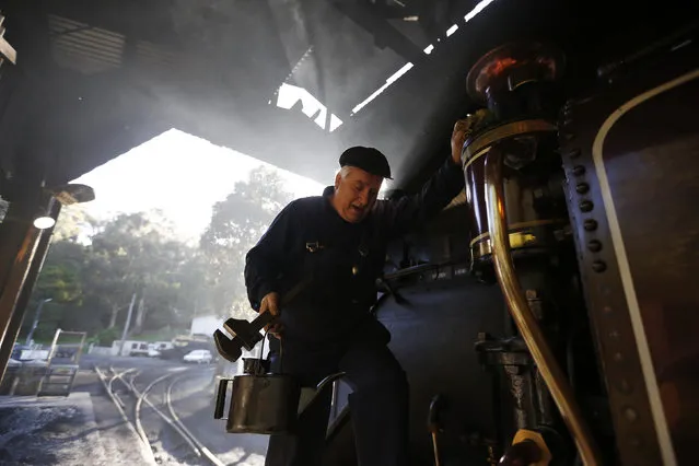 Puffing Billy steam engine driver Steve Holmes, 61, climbs down from his locomotive in the morning light during an inspection before running a train from Belgrave near Melbourne, October 20, 2014. But in one small corner of rural Australia, the sights, sounds and smells of the Industrial Revolution remain very much alive. (Photo by Jason Reed/Reuters)