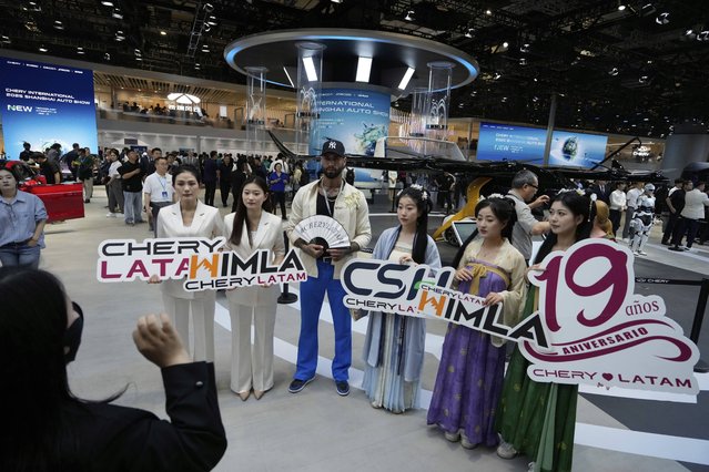Visitors holding up signs celebrating the 19th year of Chery's presence in Latin America during the Shanghai auto show on Wednesday, April 23, 2025. (Photo by Ng Han Guan/AP Photo)