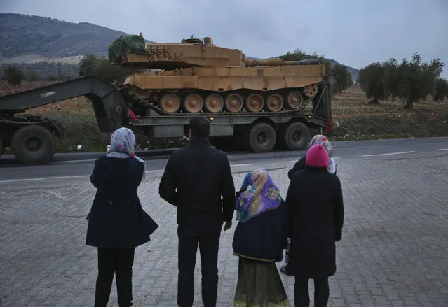 Residents watch as a truck, part of a convoy, transporting a Turkish Army tank is driven in the outskirts of the town of Kilis, Turkey, near the border with Syria, Sunday, January 21, 2018. Turkish troops and Syrian opposition forces attacked a Kurdish enclave in northern Syria on Sunday in their bid to drive from the region a U.S.-allied Kurdish militia, which responded with a hail of rockets on Turkish towns that killed at least one refugee. (Photo by Lefteris Pitarakis/AP Photo)