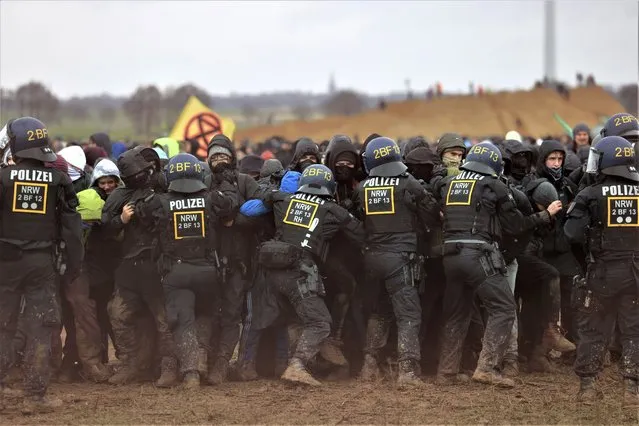 Police officers push back demonstrators on the edge of the opencast lignite mine Garzweiler at the village Luetzerath near Erkelenz, Germany, Saturday, January 14, 2023. (Photo by Oliver Berg/dpa via AP Photo)