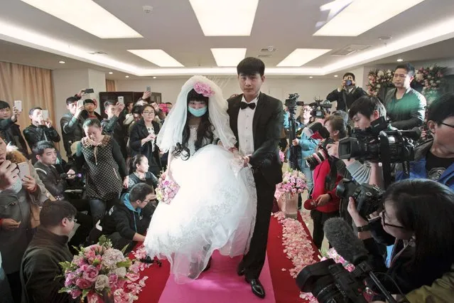 Newly-wed bride Fan Huixiang, a 25-year-old cancer patient, wearing a mask, walks on the red carpet with her groom Yu Haining, during their wedding at a hospital in Zhengzhou, Henan province, November 17, 2014. (Photo by Reuters/China Daily)