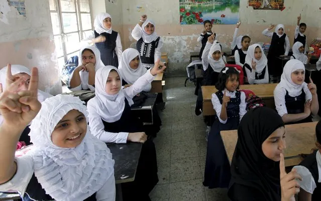 Students raise their hands while attending the first day of the new school term at a primary school in Baghdad, October 18, 2015. (Photo by Ahmed Saad/Reuters)