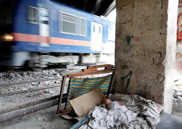 A baby sleeps in a cot while a train passes by in Santa Mesa district, Metro Manila, Philippines February 12, 2018. (Photo by Dondi Tawatao/Reuters)