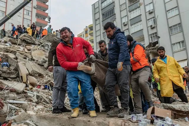 Rescuers carry a body found in the rubble in Adana on February 6, 2023, after a 7.8-magnitude earthquake struck the country's south-east. The combined death toll has risen to over 1,900 for Turkey and Syria after the region's strongest quake in nearly a century on February 6, 2023. Turkey's emergency services said at least 1,121 people died in the 7.8-magnitude earthquake, with another 783 confirmed fatalities in Syria, putting that toll at 1,904. (Photo by Can Erok/AFP Photo)