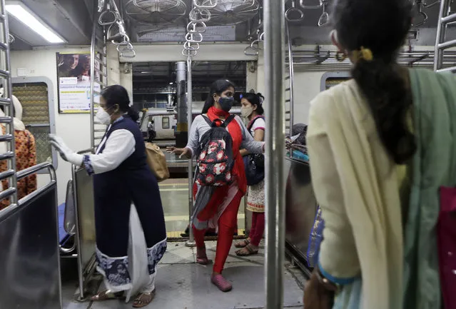 Women passengers enter a local train in Mumbai, India, Wednesday, October 21, 2020. Indian railways has permitted women passengers to travel in local trains during non-peak hours beginning Wednesday, which otherwise has been running only for essential services. (Photo by Rajanish Kakade/AP Photo)