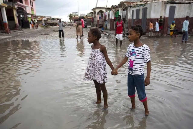 Girls hold hands as they help each other wade through a flooded street after the passing of Hurricane Matthew in Les Cayes, Haiti, Thursday, October 6, 2016. Two days after the storm rampaged across the country's remote southwestern peninsula, authorities and aid workers still lack a clear picture of what they fear is the country's biggest disaster in years. (Photo by Dieu Nalio Chery/AP Photo)