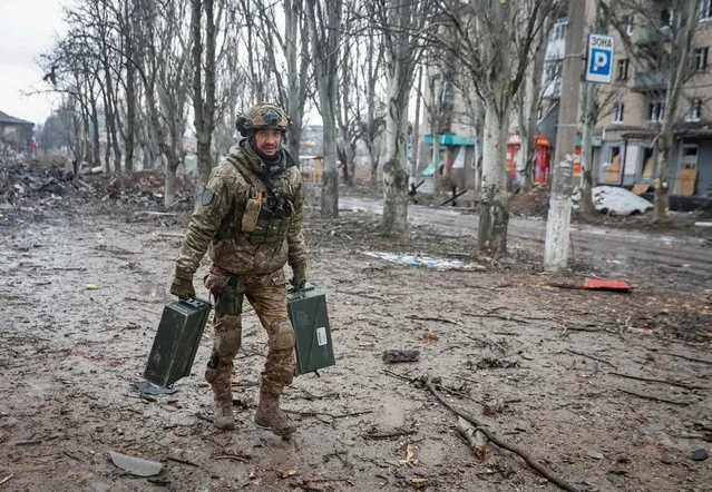 A Ukrainian serviceman carries weapons on an empty street in the front line city of Bakhmut, in Donetsk region, Ukraine on February 25, 2023. (Photo by Serhii Nuzhnenko/Radio Free Europe/Radio Liberty)