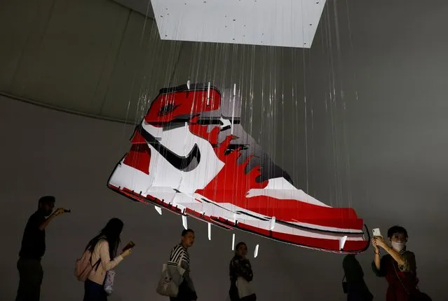 People take photos of artist Michael Murphy's recycled cardboard Air Jordan 1 Chicago sculpture “Air” during the media preview of Sneakertopia, a sneaker and street culture exhibition, at the Art Science Museum in Singapore on February 23, 2023. (Photo by Edgar Su/Reuters)