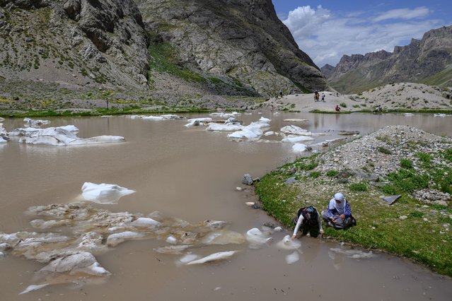 A woman touches a piece of melting ice on the Cilo glacier of Turkey's southeastern Hakkari province on July 13, 2025. As global temperatures rise amid human-caused climate change, new sections of the mountains that were once capped in ice are melting fast year after year. A UN report on desertification worldwide estimates that 88 percent of Turkey's territory is at risk: rainfall is expected to decrease by 30 percent by the end of the century, while temperatures are expected to rise by 5 to 6C compared to the averages recorded between 1961 and 1990. (Photo by Yasin Akgul/AFP Photo)