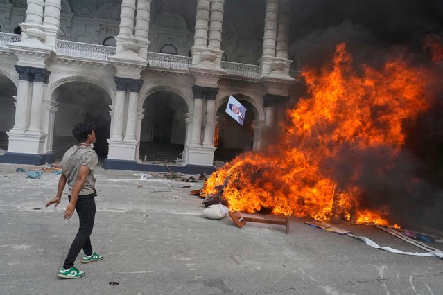 A protester throws a photograph of Nepal Prime Minister Khadga Prasad Oli in the fire at the Singha Durbar, the seat of Nepal's government's various ministries and offices during a protest against social media ban and corruption in Kathmandu, Nepal, Tuesday, September 9, 2025. (Photo by Niranjan Shrestha/AP Photo)
