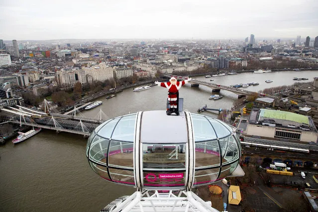 A man dressed as Santa Claus poses some 135 meters in the air on a pod of the London Eye, to kick-off the festive season, in London, Thursday December 9, 2020. The London Eye tourist attraction, which has reopened to the public as coronavirus restrictions are relaxed, offers 360-degree views, with the River Thames, Waterloo Bridge at centre, and City of London background right. (Photo by David Parry/PA Wire via AP Photo)