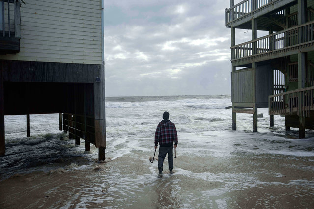 A worker who is reinforcing a home at risk of falling into the ocean looks out toward the waves as a storm approaches Friday, October 10, 2025, in Buxton, N.C. (Photo by Allison Joyce/AP Photo)