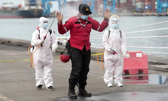 Members of Indonesian Red Cross spray a rescuer with disinfectant after sorting parts of aircraft and debris retrieved from from the Java Sea where a Sriwijaya Air jet crashed on Saturday, at Tanjung Priok Port in Jakarta, Indonesia, Thursday, January 14, 2021. An aerial search for victims and wreckage of a crashed Indonesian plane expanded Thursday as divers continued combing the debris-littered seabed looking for the cockpit voice recorder from the lost Sriwijaya Air jet. (Photo by Dita Alangkara/AP Photo)