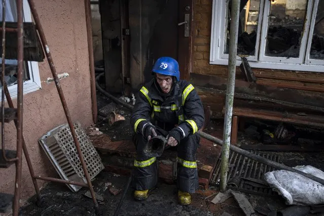 A Ukrainian firefighter takes a break from extinguishing a fire inside a house destroyed by shelling in Kyiv, Ukraine, Wednesday, March 23, 2022. (Photo by Rodrigo Abd/AP Photo)
