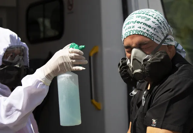 Paramedics Carolina Estrada, left, disinfects her partner Elvin Munguia after mobilizing a COVID-19 patient from his home to a hospital in the Iztapalapa district of Mexico City, Tuesday, February 2, 2021. (Photo by Marco Ugarte/AP Photo)