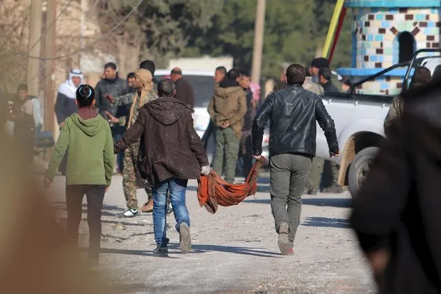 Residents carry human remains in a cloth from a site hit by one of three truck bombs, in the YPG-controlled town of Tel Tamer, Syria December 11, 2015. A spokesman for the Syrian Kurdish YPG militia said the death toll from a triple truck bomb attack in a town in northeastern Syria on Friday had risen to 50 to 60 people, with more than 80 others wounded. One of the blasts occurred outside a hospital, another at a market and the third in a residential area in the YPG-controlled town of Tel Tamer, Redur Xelil said via Internet messaging service. (Photo by Rodi Said/Reuters)