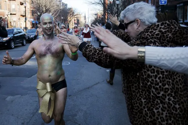 An onlooker high fives participants in the 16th annual Santa Speedo Run through the Back Bay in Boston, Massachusetts, December 12, 2015. (Photo by Brian Snyder/Reuters)
