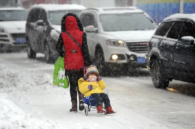 A woman pulls a cart carrying a child on a snow-covered street as heavy snowfall hit Urumqi, Xinjiang Uighur Autonomous Region, China, December 11, 2015. Picture taken December 11, 2015. (Photo by Reuters/Stringer)
