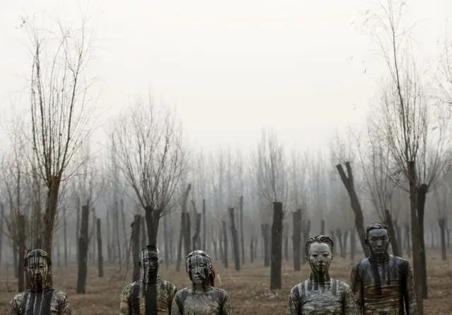 Models painted in camouflage colours to blend in with the background pose for Chinese artist Liu Bolin's artwork "“Dongji”, or Winter Solstice, on the second day after China's capital Beijing issued its second ever “red alert” for air pollution, in Beijing, China, December 20, 2015. (Photo by Kim Kyung-Hoon/Reuters)