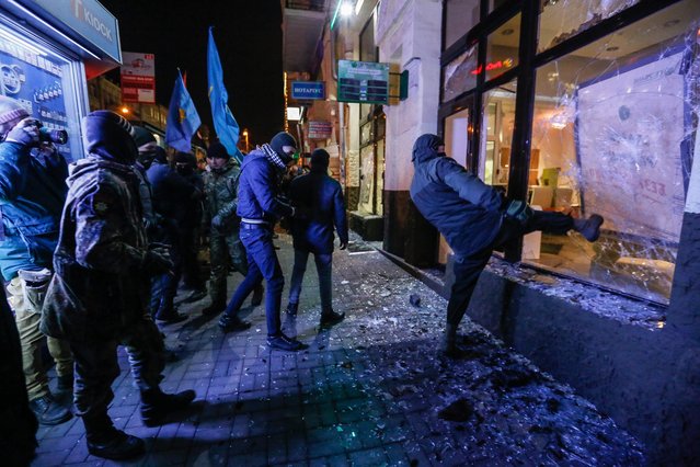 Activists and supporters of Ukrainian nationalist groups brake a window of the Russian bank Sberbank during a rally to mark the third anniversary of the Euromaidan Revolution in Kiev, Ukraine, 21 November 2016. (Photo by Roman Pilipey/EPA)