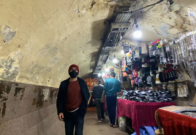 A man wearing a protective face mask walks in a tunnel besides street vendors in Shubra El Kheima, Al Qalyubia Governorate, north of Cairo, amid the coronavirus disease (COVID-19) outbreak, Egypt on January 5, 2021. (Photo by Mohamed Abd El Ghany/Reuters)