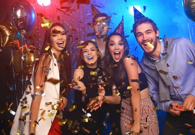 Friends making big party in the night. Four people throwing confetti and drinking champagne. (Photo by OPOLJA/Rex Features/Shutterstock)