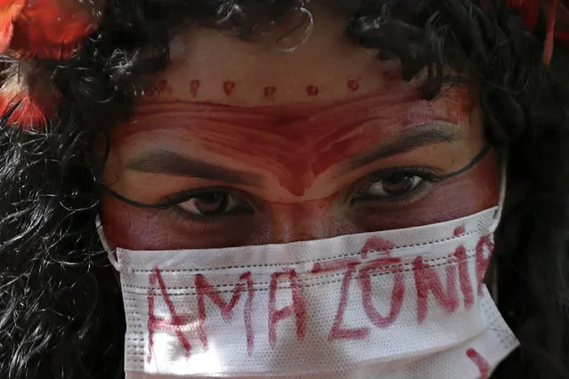 An Indigenous woman wears a protective face mask as a precaution against COVID-19 during a protest against Brazilian President Jair Bolsonaro's proposals to allow mining on Indigenous lands, at the Esplanade of Ministries in Brasilia, Brazil, Tuesday, April 20, 2021. (Photo by Eraldo Peres/AP Photo)