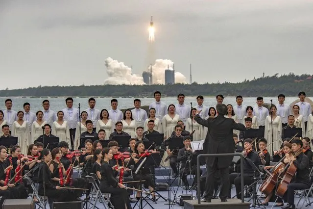 Members of the Xian Symphony Orchestra and Chorus perform during the launch of the Long March 5B rocket (back) carrying China's Tianhe space station core module from the Wenchang Spacecraft Launch Site in Hainan Province, China, 29 April 2021. China launched into space the core module of its space station, marking the beginning of a series of launch missions to complete the space station by the end of next year. (Photo by Matjaz Tancic/EPA/EFE)