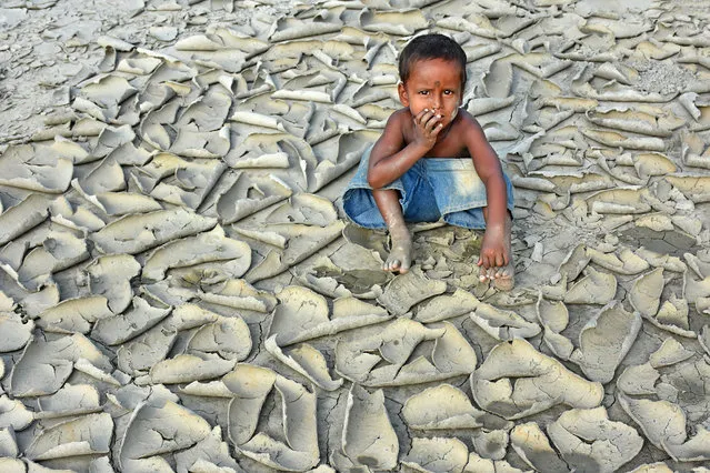 Dryness by Chinmon Biswas, India, winner of the changing climates prize. A child sits on drought-stricken land that has become cracked and scaly. Long dry spells can cause the earth to remain open underground, even after the surface has sealed. (Photo by Chinmoy Biswas/2018 Ciwem environmental photographer of the year 2018)