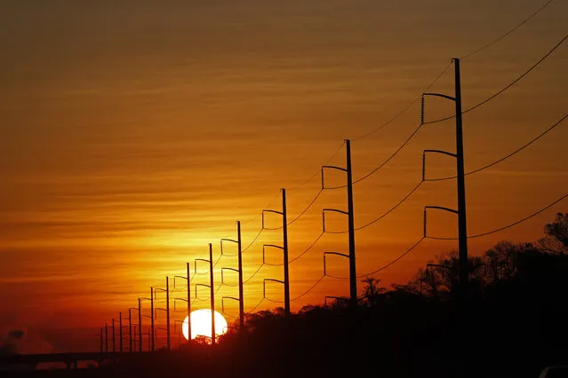 In this January 31, 2018, file photo, the sun rises beyond power lines in St. Charles Parish, La. Homeland Security officials say that Russian hackers used conventional tools to trick victims into entering passwords in order to build out a sophisticated effort to gain access to control rooms of utilities in the U.S. The victims included hundreds of vendors that had links to nuclear plants and the electrical grid. (Photo by Gerald Herbert/AP Photo)