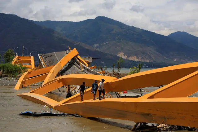 People walk on a broken bridge after it was hit by an earthquake and tsunami last week in Palu, Sulawesi island, Indonesia October 7, 2018. (Photo by Reuters/Beawiharta)
